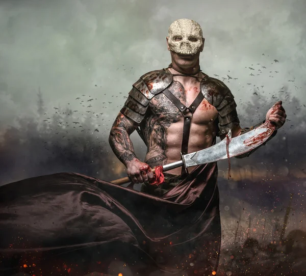Мужчина в маске черепа держит меч — стоковое фото