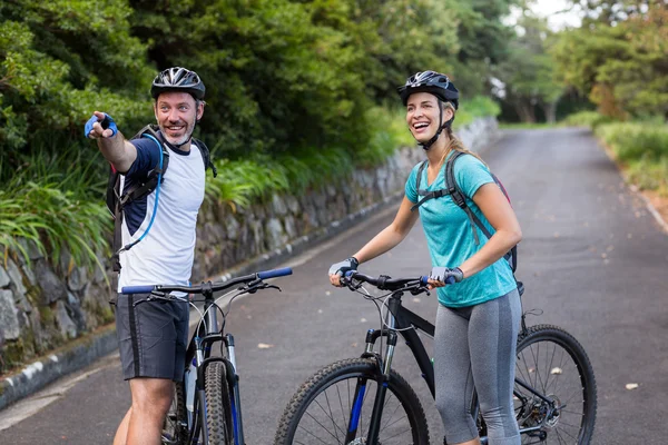Спортивная(ый) пара с горный велосипед, указывая на расстоянии — стоковое фото