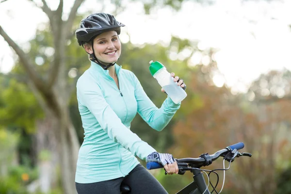 Красивые девушки велосипедист питьевой воды в лесу — стоковое фото