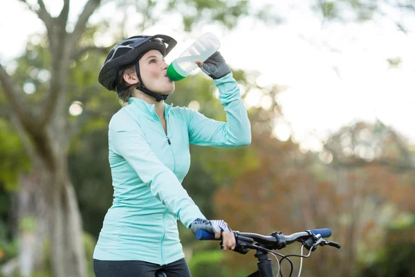 Женщины велосипедист питьевой воды в лесу — стоковое фото