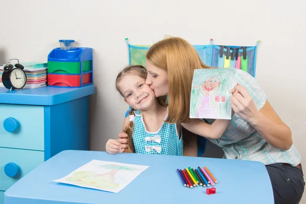 Mum kisses the daughter because she drew her beautiful — стоковое фото