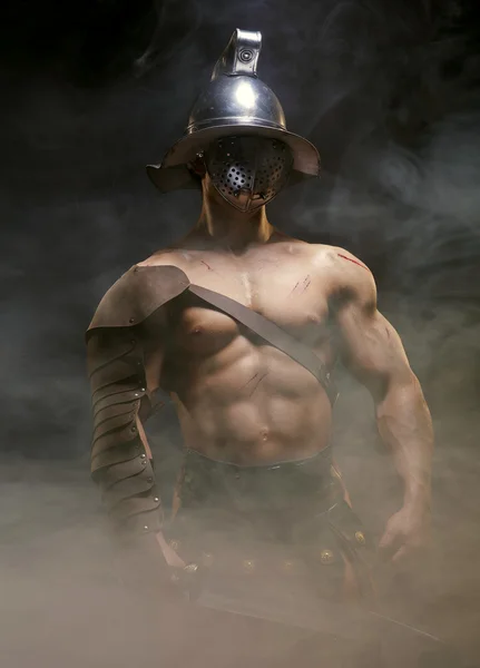Гладиатор, стоящий в дыме со шлемом и мечом — стоковое фото