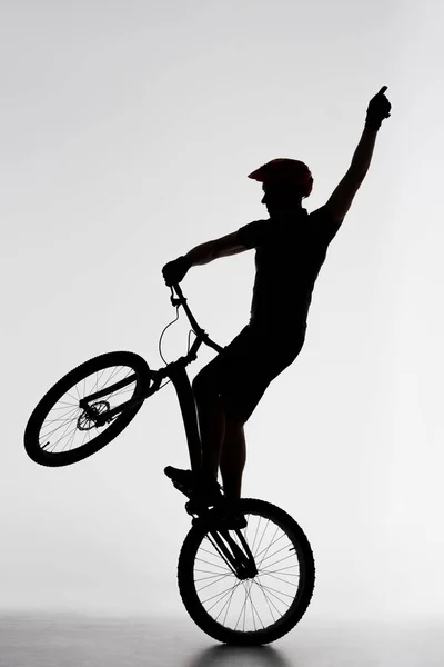 Силуэт Пробную Велосипедист Стоя Заднем Колесе Поднимая Руку Белом — стоковое фото