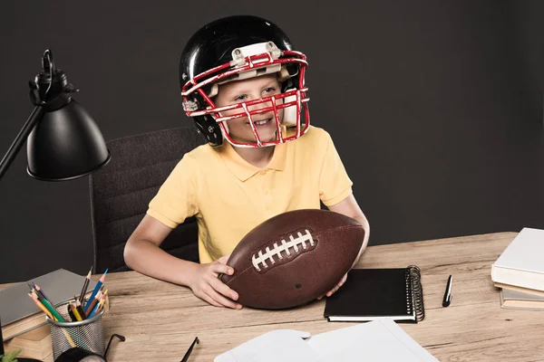 Adorable Schoolboy American Football Helmet Sitting Table Ball Books Lamp Лицензионные Стоковые Изображения